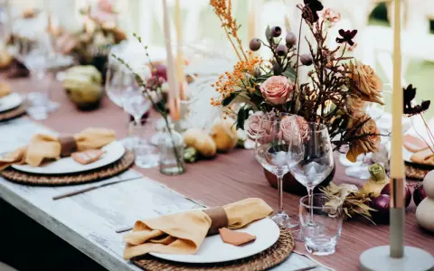 Magnifique table dressée avec des fleurs, des bougies et des serviettes en lin ocre. Idées de décoration de table pour un repas chaleureux.