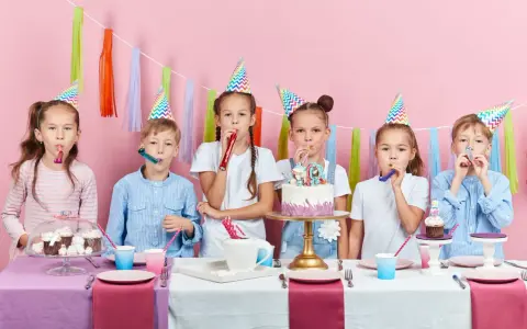 Six enfants joyeux célèbrent un anniversaire 11 ans, portant des chapeaux de fête et soufflant dans des cotillons devant un gâteau décoré.