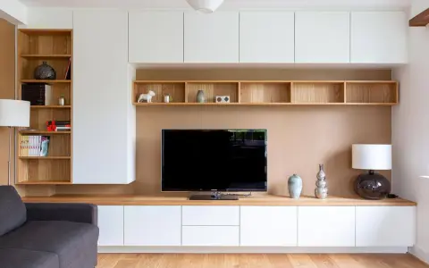 Un coin TV optimisé pour un petit espace, avec des étagères en bois et des rangements blancs.