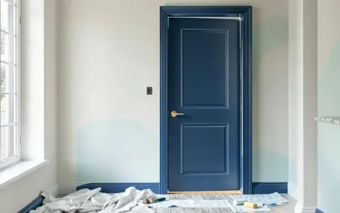 Une porte intérieure bleu marine est peinte, contrastant avec les murs clairs et les touches de bleu pâle. Le projet de peindre porte intérieure 2 couleurs est en cours.
