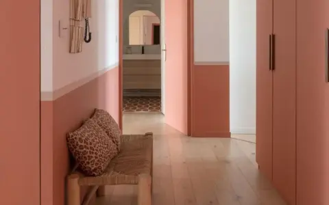 Banc en rotin avec coussins léopard, murs bicolores corail et blanc, portes roses. Une belle idée déco couloir moderne.