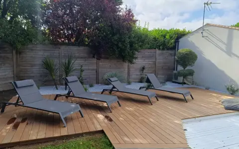 Quatre chaises longues grises attendent sur les plus belles terrasses en bois, invitant à la détente sous le soleil.