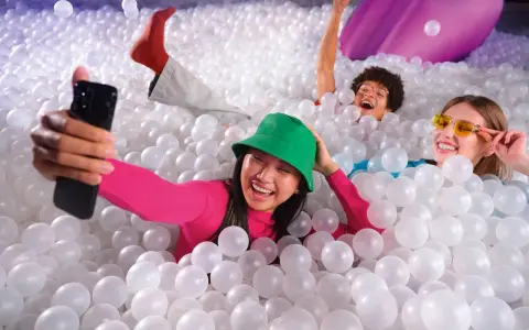 Trois amis s'amusent dans une piscine à balles, une expérience digne d'une **bubble planet Paris**.
