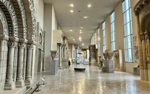 Vaste galerie de la Cité de l'architecture et du patrimoine, présentant des éléments architecturaux romans et gothiques, avec des colonnes sculptées et des arcs en plein cintre.