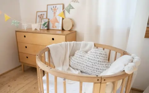 Aménagement chambre enfant : berceau en bois, coussin nuage, plaid douillet et commode vintage. Guirlande de fanions joyeuse.