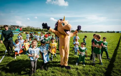 Un costume de licorne géant accueille des enfants costumés pour une journée de jeux à l'hippodrome en famille.