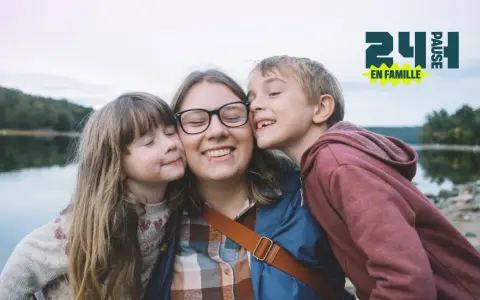Une mère et ses deux enfants s'embrassent près d'un lac. Une belle idée pour savoir que faire le 1er mai en famille.