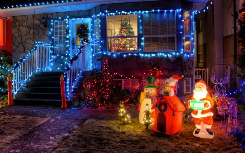 La maison est parée des plus belles décorations de Noël extérieur : guirlandes bleues, Père Noël, bonhomme de neige, renne et sapins illuminés.
