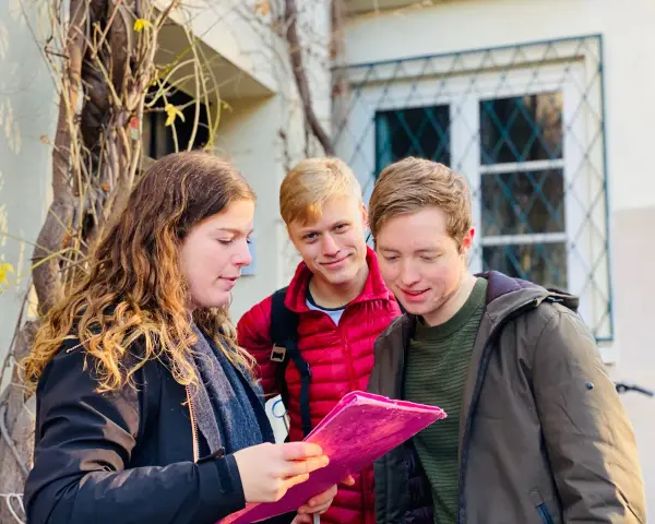 Trois amis consultent une carte rose, prêts pour leur escape game Montmartre.