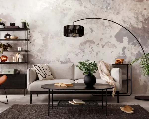 Salon industriel cocooning : canapé gris, fauteuil orange, étagère noire, table basse noire, tapis sombre, mur texturé.