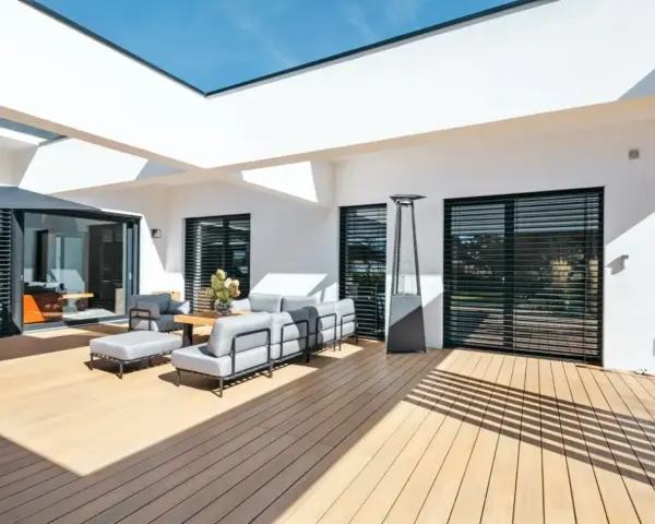 Aménagement d'une **décoration terrasse extérieure moderne** avec salon gris, table basse en bois, parasol chauffant et sol en bois clair.
