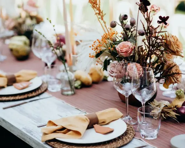 Magnifique table dressée avec des fleurs, des bougies et des serviettes en lin ocre. Idées de décoration de table pour un repas chaleureux.
