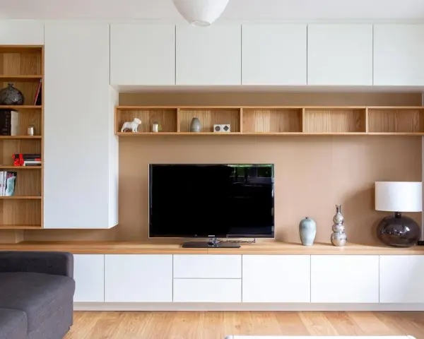 Un coin TV optimisé pour un petit espace, avec des étagères en bois et des rangements blancs.