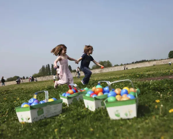 Deux enfants courent joyeusement dans un champ fleuri, leurs paniers remplis d'œufs colorés, signe d'une joyeuse chasse aux œufs.