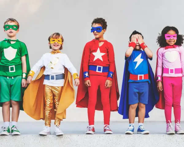 Cinq enfants déguisés en super-héros, avec des capes et des masques colorés.