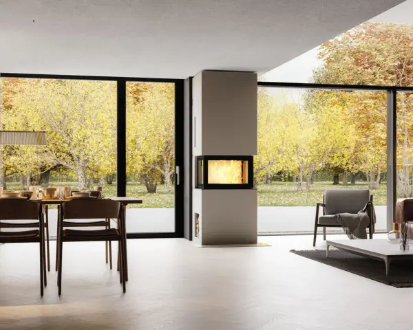 Un salon moderne avec une cheminée design, une table à manger et de grandes baies vitrées offrant une vue sur un jardin d'automne. Idéal pour moderniser une cheminée.