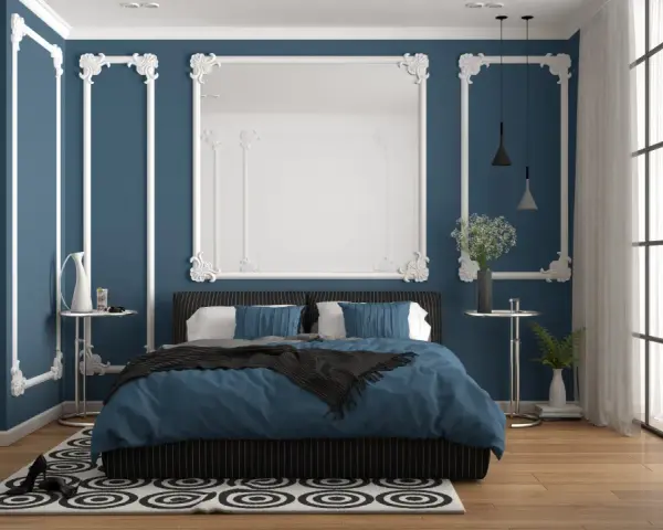 Chambre élégante avec murs bleu nuit et moulures blanches. Le lit est paré de linge de lit bleu roi, créant 2 couleurs qui vont bien ensemble pour une chambre.