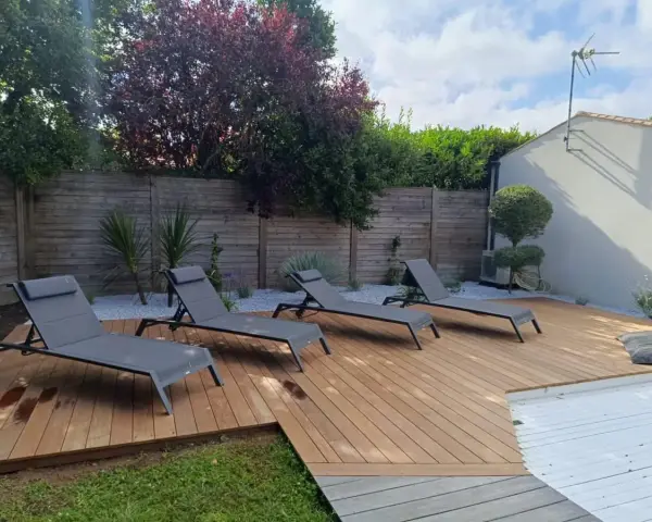 Quatre chaises longues grises attendent sur les plus belles terrasses en bois, invitant à la détente sous le soleil.
