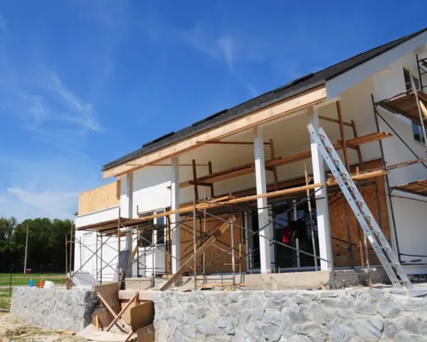Chantier d'une maison en cours de rénovation, avec échafaudages et une échelle. Projet d'agrandissement de maison en vue.