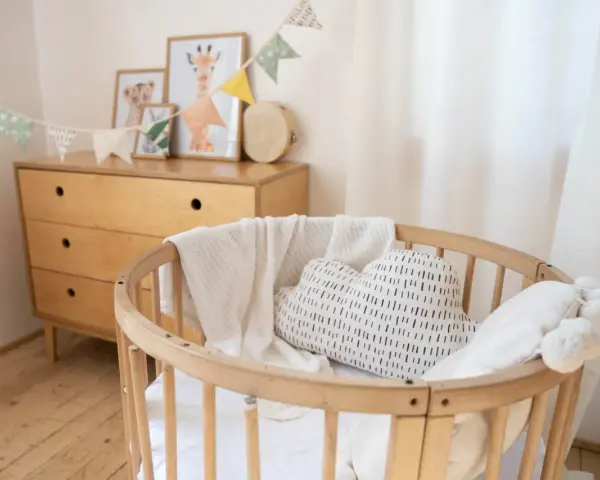 Aménagement chambre enfant : berceau en bois, coussin nuage, plaid douillet et commode vintage. Guirlande de fanions joyeuse.