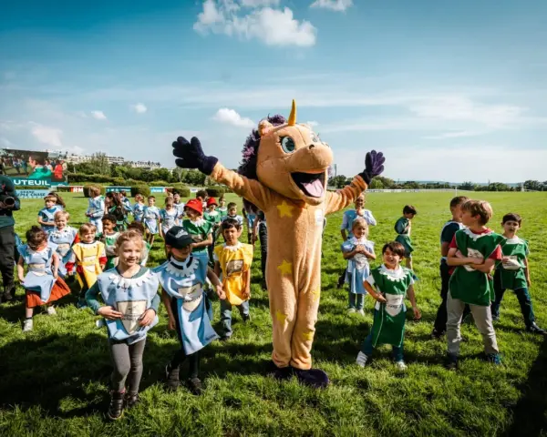 Un costume de licorne géant accueille des enfants costumés pour une journée de jeux à l'hippodrome en famille.