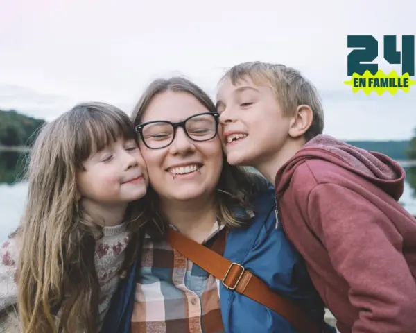 Une mère et ses deux enfants s'embrassent près d'un lac. Une belle idée pour savoir que faire le 1er mai en famille.