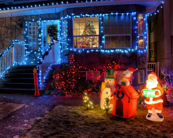 La maison est parée des plus belles décorations de Noël extérieur : guirlandes bleues, Père Noël, bonhomme de neige, renne et sapins illuminés.