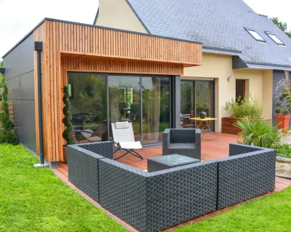 Agrandissement maison ossature bois avec terrasse moderne et mobilier extérieur.