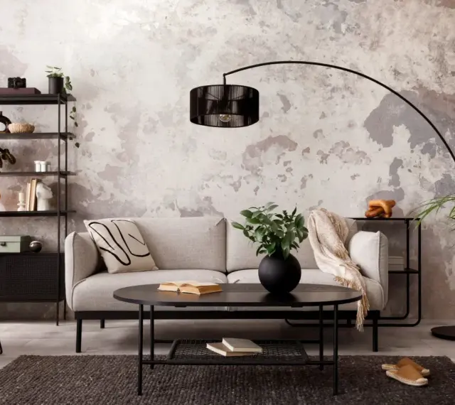 Salon industriel cocooning : canapé gris, fauteuil orange, étagère noire, table basse noire, tapis sombre, mur texturé.