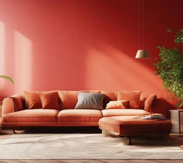 Un salon chaleureux aux murs rouge corail, avec un canapé orange vif et des plantes vertes. Une ambiance qui annonce la couleur tendance 2026.