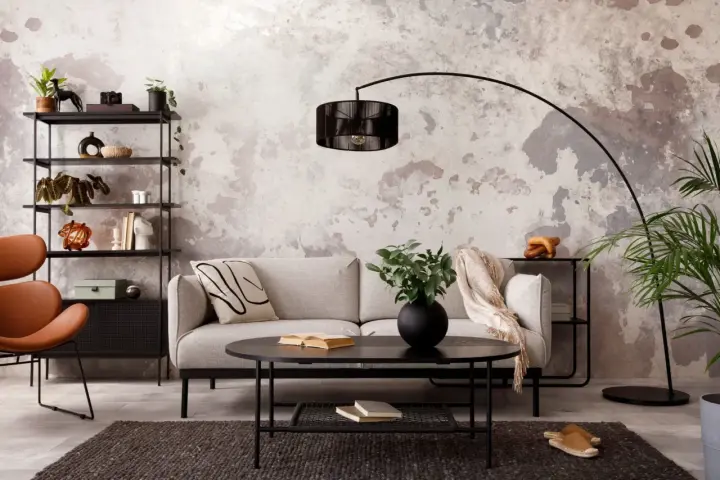 Salon industriel cocooning : canapé gris, fauteuil orange, étagère noire, table basse noire, tapis sombre, mur texturé.