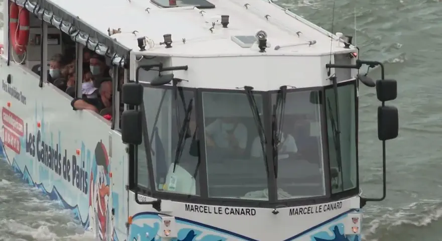 Le bus amphibie "Les Canards de Paris" navigue sur l'eau, transportant des touristes masqués pour une visite unique de la ville.