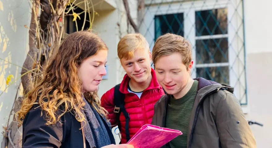 Trois amis consultent une carte rose, prêts pour leur escape game Montmartre.