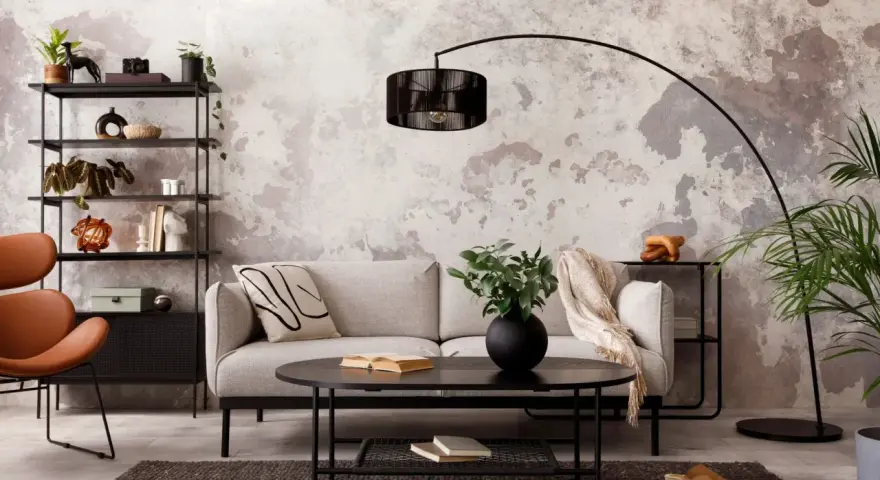 Salon industriel cocooning : canapé gris, fauteuil orange, étagère noire, table basse noire, tapis sombre, mur texturé.