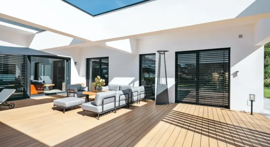 Aménagement d'une **décoration terrasse extérieure moderne** avec salon gris, table basse en bois, parasol chauffant et sol en bois clair.