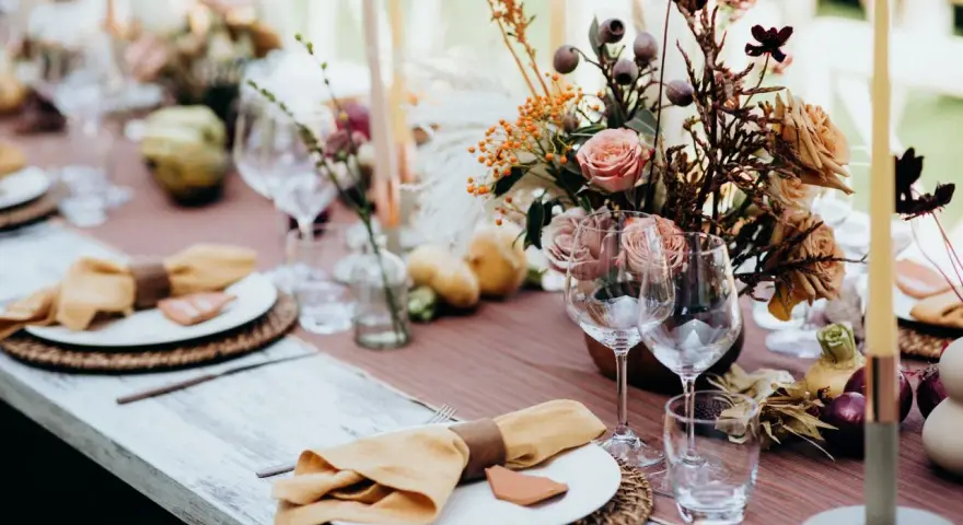 Magnifique table dressée avec des fleurs, des bougies et des serviettes en lin ocre. Idées de décoration de table pour un repas chaleureux.
