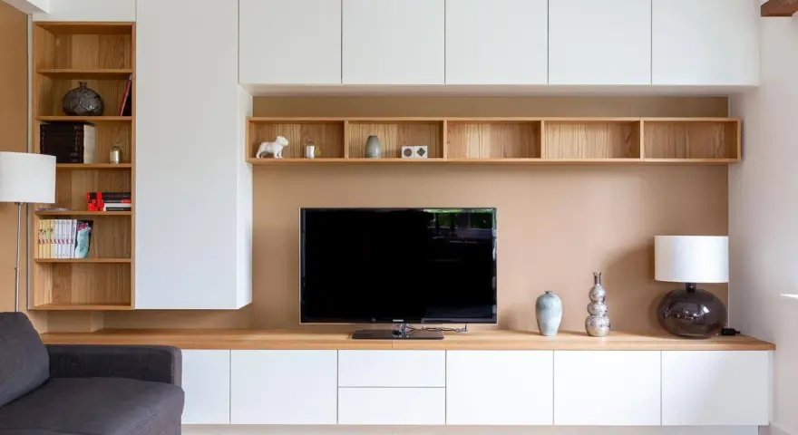 Un coin TV optimisé pour un petit espace, avec des étagères en bois et des rangements blancs.