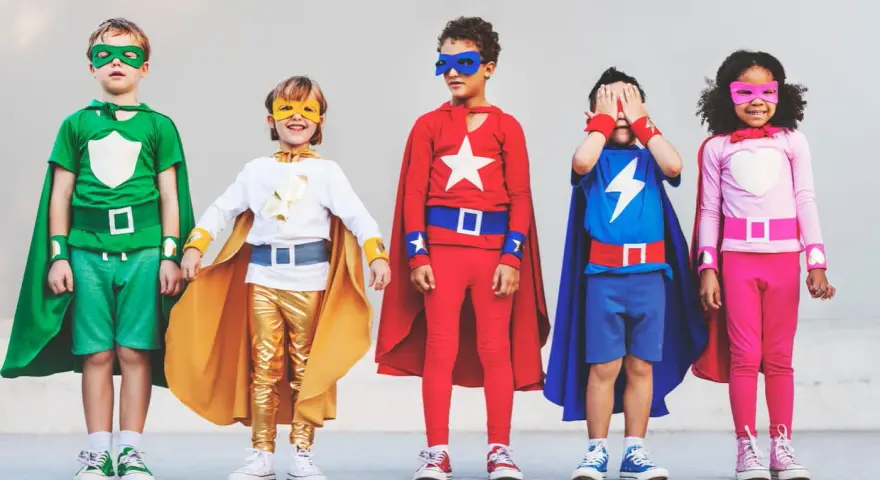Cinq enfants déguisés en super-héros, avec des capes et des masques colorés.