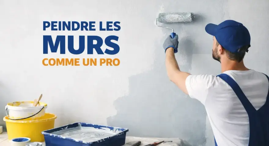 Un peintre en combinaison bleue utilise un rouleau pour repeindre un mur en blanc. Des pots de peinture et des pinceaux sont disposés sur une table.
