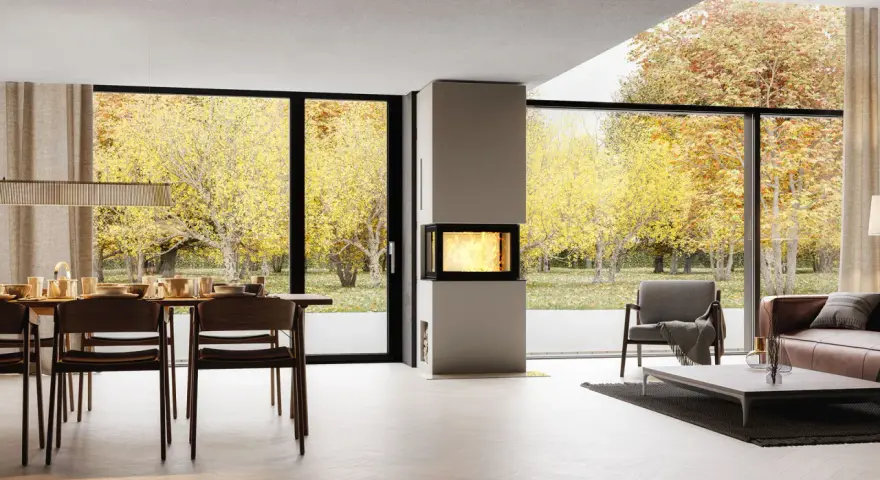 Un salon moderne avec une cheminée design, une table à manger et de grandes baies vitrées offrant une vue sur un jardin d'automne. Idéal pour moderniser une cheminée.