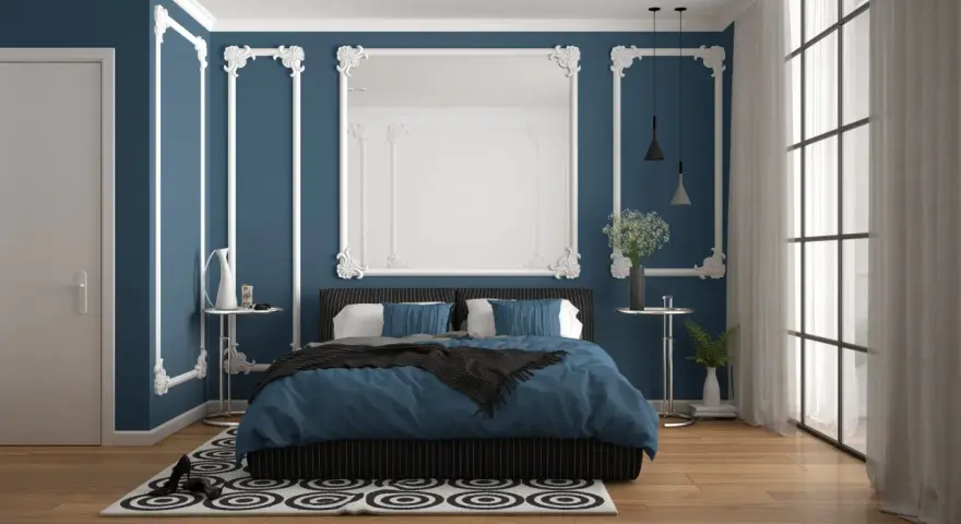 Chambre élégante avec murs bleu nuit et moulures blanches. Le lit est paré de linge de lit bleu roi, créant 2 couleurs qui vont bien ensemble pour une chambre.