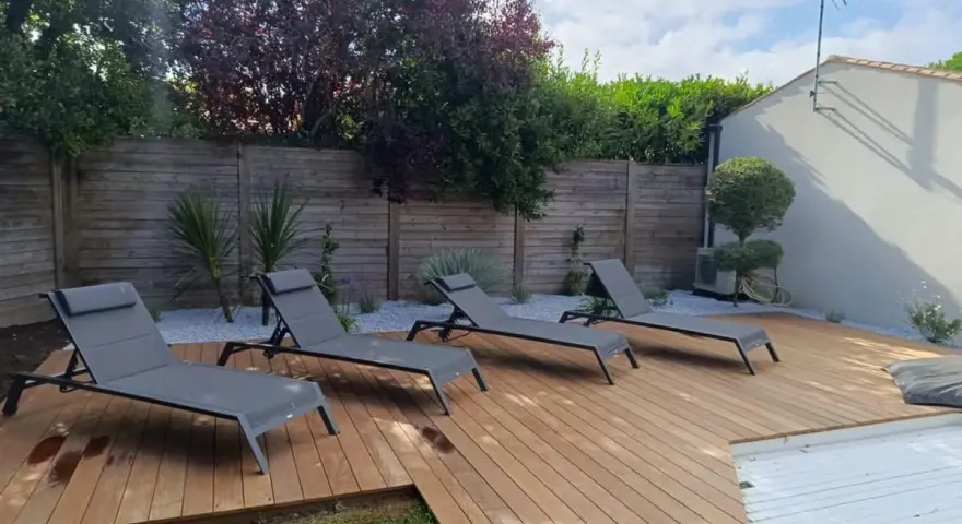 Quatre chaises longues grises attendent sur les plus belles terrasses en bois, invitant à la détente sous le soleil.