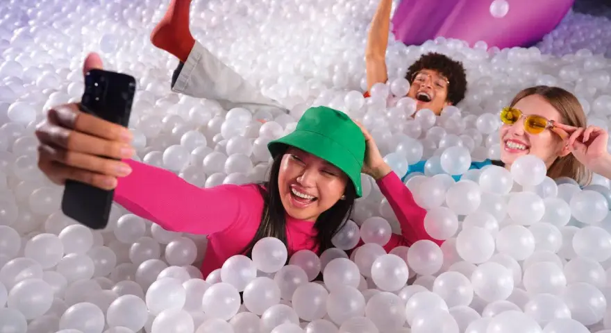 Trois amis s'amusent dans une piscine à balles, une expérience digne d'une **bubble planet Paris**.
