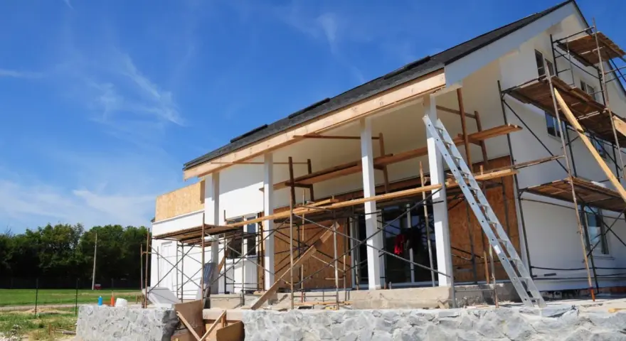 Chantier d'une maison en cours de rénovation, avec échafaudages et une échelle. Projet d'agrandissement de maison en vue.