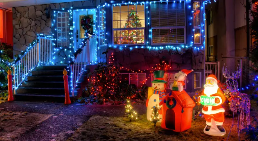 La maison est parée des plus belles décorations de Noël extérieur : guirlandes bleues, Père Noël, bonhomme de neige, renne et sapins illuminés.