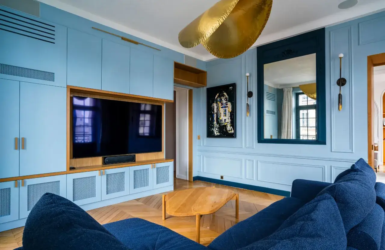Salon bleu pastel avec meuble TV intégré, canapé en velours bleu nuit et un tableau de R2-D2. On dirait qu'ils ont décidé de peindre 2 murs sur 4.