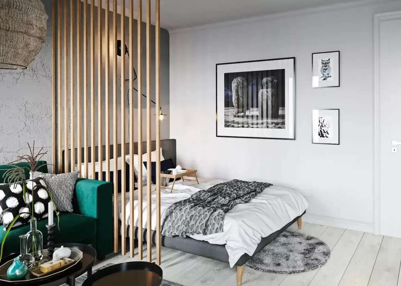 Une chambre moderne avec un séparateur en bois pour séparer une chambre pour 2 ados. Un canapé vert, un lit, et des tableaux aux murs.