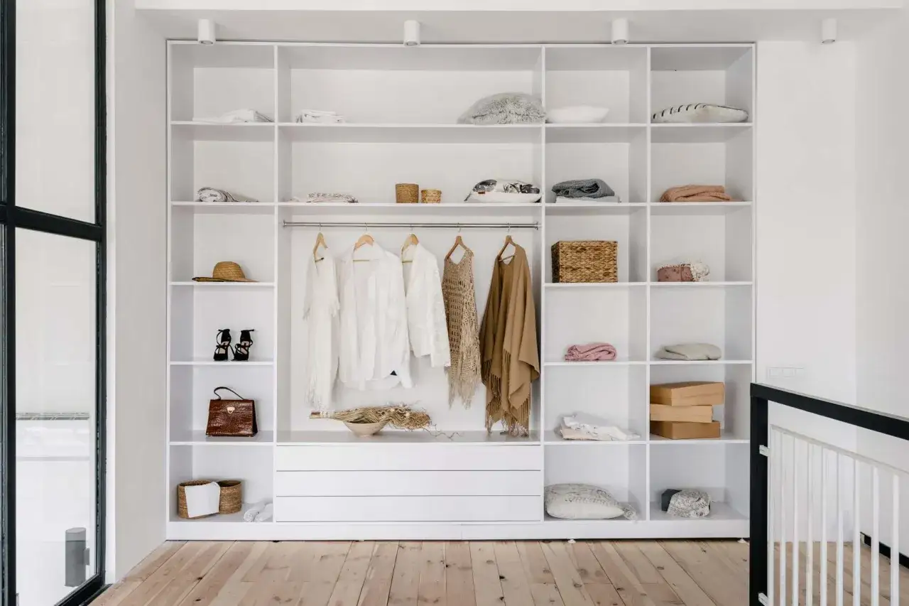 Un dressing blanc épuré, idéal pour apprendre comment ranger son dressing. Vêtements suspendus, étagères organisées avec des paniers et des boîtes.
