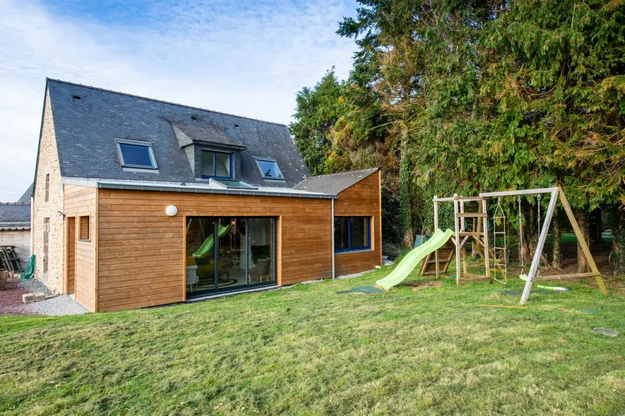 Agrandissement maison ossature bois avec jardin et jeux d'enfants.