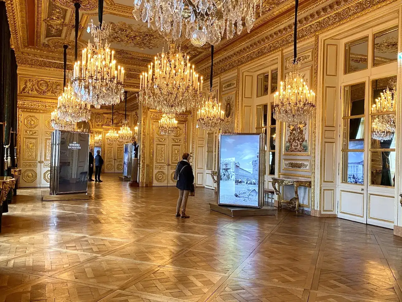 Intérieur doré du hôtel de la Marine, avec des lustres étincelants, des panneaux muraux ornés et des expositions.